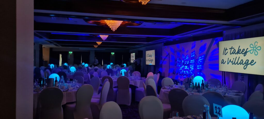 A blue lit room with circular tables laid out for dining