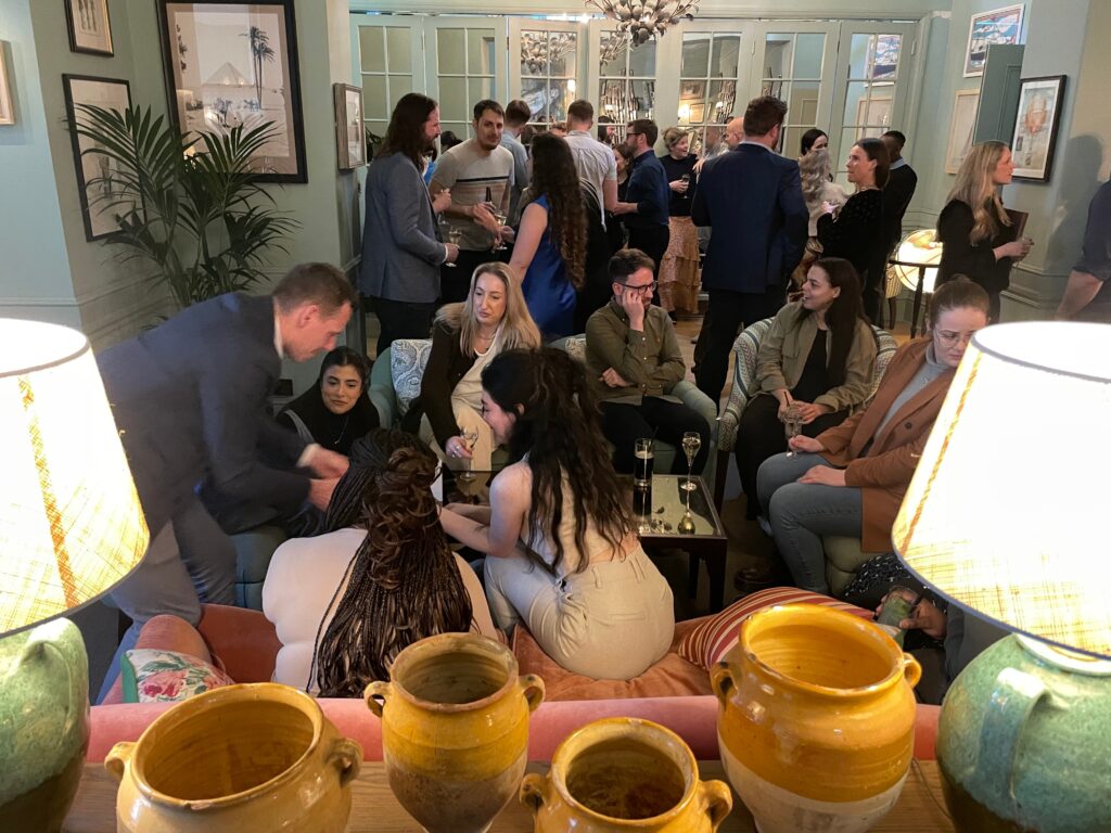 A group of people gathered in a room, dressed in smart-casual attire enjoying conversation